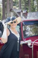 mujer atractiva en traje de los años veinte cerca de automóviles antiguos foto
