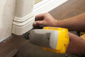 Nailing New Baseboard with Bull Nose Corners and New Laminate Flooring photo