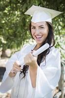 niña de raza mixta graduada en toga y birrete con diploma foto