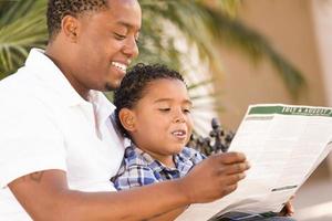 padre e hijo de raza mixta leyendo el folleto del parque afuera foto