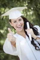 niña de raza mixta graduada en toga y birrete con diploma foto