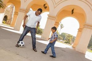 padre e hijo de raza mixta jugando al fútbol en el patio foto