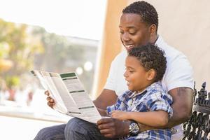 padre e hijo de raza mixta leyendo el folleto del parque afuera