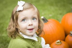 linda niña pequeña disfrutando del huerto de calabazas. foto