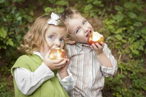 adorable hermano y hermana niños comiendo manzanas afuera foto