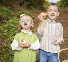 adorables niños comiendo manzanas rojas afuera foto
