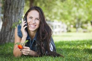 hembra joven de raza mixta hablando por teléfono celular afuera foto