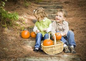 Brother and Sister Children Sitting on Wood Steps with Pumpkins photo