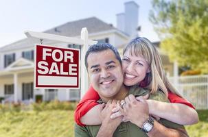 pareja frente al letrero de venta y la casa foto