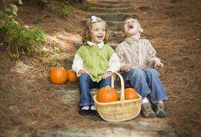 Hermano y hermana niños sentados en escalones de madera con calabazas foto