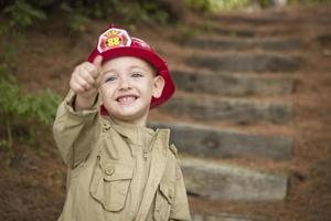 adorable niño con sombrero de bombero jugando afuera foto