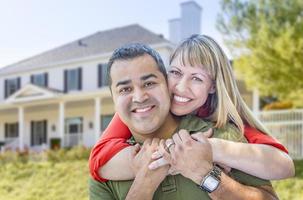 feliz pareja de raza mixta en frente de la casa foto