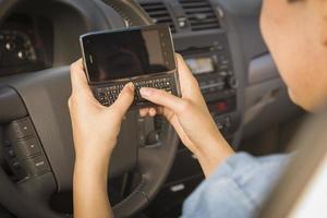 mujer de raza mixta enviando mensajes de texto y conduciendo foto