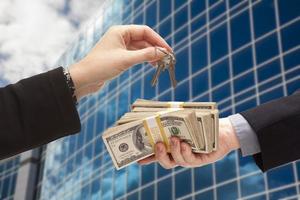 Handing Stack of Cash For Key and Corporate Building photo