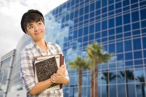 Mixed Race Female Student Holding Books in Front of Building photo