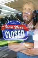 Sad Female Store Owner Turning Sign to Closed in Window photo