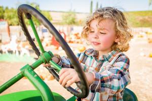 Little Boy Having Fun In A Tractor in a Rustic Ranch Setting at the Pumpkin Patch. photo