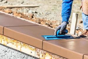 Construction Worker Using Trowel On Wet Cement Forming Coping Around New Pool photo