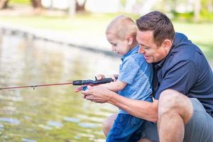 joven caucásico padre e hijo divirtiéndose pescando en el lago foto
