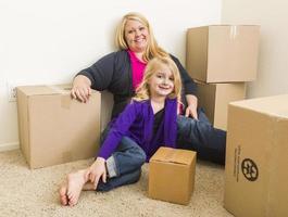 Young Mother and Daughter In Empty Room With Moving Boxes photo