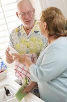 Senior Adult Couple Washing Dishes Together Inside Kitchen photo