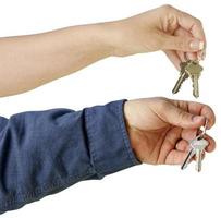 Man and Woman handing over house keys on a white background. photo