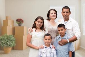 Hispanic Family in Empty Room with Packed Moving Boxes and Potted Plants photo