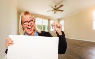 Attractive Young Woman with New Keys and Blank Board In Empty Room of House photo