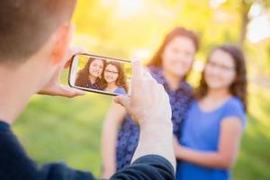 Hispanic Father Taking Picture of Mother and Daughter with Cell Phone photo