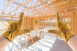 Male Contractor Hands Framing Unfinished House Framing At Construction Site photo