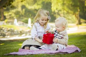 la niña le da un regalo a su hermanito en el parque foto