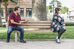 Unhappy Mixed Race Couple Sitting Facing Away From Each Other on Park Bench photo
