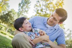 Loving Father Tickling Son in the Park photo