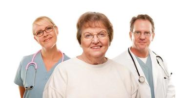 mujer mayor sonriente con médico y enfermera detrás foto