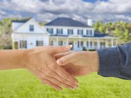 Man and Woman Shaking Hands in Front of New House photo