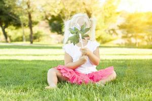 Little Girl In Grass Blowing On Pinwheel photo