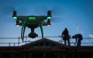 Silhouette of Unmanned Aircraft System UAV Quadcopter Drone In The Air at Construction Site photo