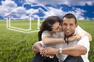 Hispanic Couple Sitting in Grass Field with Ghosted House Behind photo