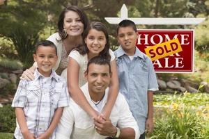 Hispanic Family in Front of Sold Real Estate Sign photo