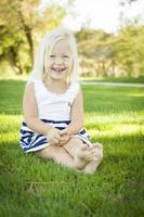 Cute Little Girl Sitting and Laughing in the Grass photo