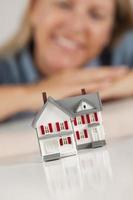 Smiling Woman Behind Model House on a White Surface photo