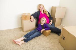 Young Mother and Daughter In Empty Room With Moving Boxes photo