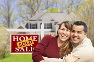 Couple in Front of Sold Real Estate Sign and House photo