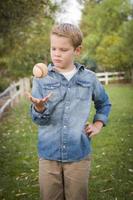 Un joven apuesto lanzando béisbol en el parque. foto