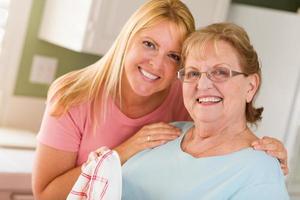 Portrait of Smiling Senior Adult Woman and Young Daughter At Sink in Kitchen photo