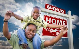 African American Father with Son In Front of Sold Home For Sale Real Estate Sign photo