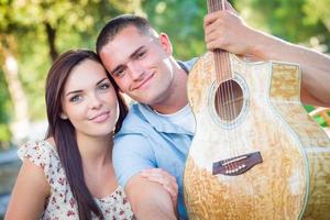 retrato de pareja de adultos jóvenes con guitarra en el parque. foto