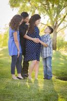 feliz y atractiva familia hispana con su madre embarazada al aire libre foto