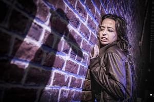 Male Shadow Figure With Knife Threatens Frightened Young Woman Against Brick Wall photo