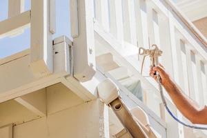 Professional House Painter Wearing Facial Protection Spray Painting Deck of A Home photo